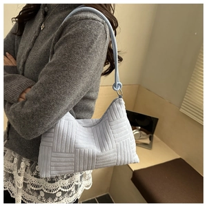 Detail of light blue hobo bag with textured embossed knit fabric on model shoulder