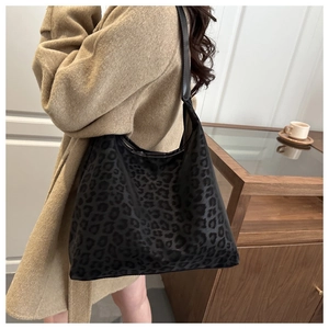 Close-up of leopard print tote bag with faux fur texture on a shoulder in indoor setting