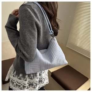 Macro detail of light blue dumpling bag featuring geometric embossed texture and side knot