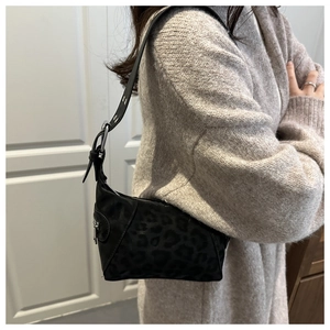 Detail of black leopard print shoulder bag with silver buckle on leather strap