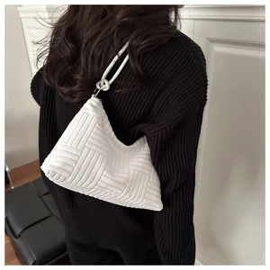Détail du sac bandoulière blanc tissé avec sangle nouée sur l'épaule d'un modèle