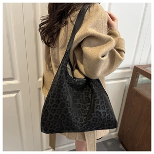 Detailed close-up of leopard print shoulder bag with adjustable wide strap on a model