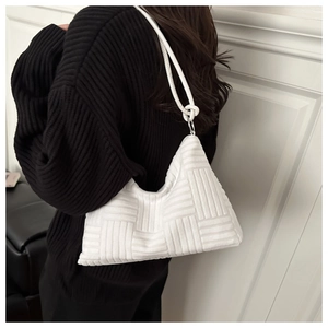 Détail du sac hobo blanc avec texture tissée et poignée nouée sur un pull noir