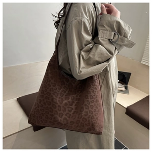 Detailed texture of leopard print tote bag in soft suede fabric worn over a trench coat