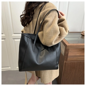 Model zeigt eine große schwarze Shopper-Tasche aus Kunstleder mit zwei Schultergurten