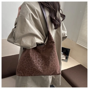 Close-up detail of the soft leopard print fabric and brown shoulder strap of the tote bag