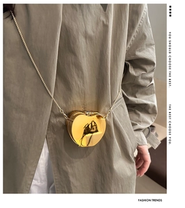 Chic gold apple-shaped mini crossbody bag styled on a khaki trench coat for fashion decor