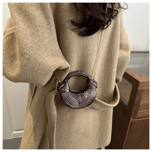 Dettaglio pochette in acrilico bronzo con trama a righe e manico ad anello dorato