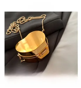 Close-up of golden heart-shaped evening bag with polished mirror finish and metal chain
