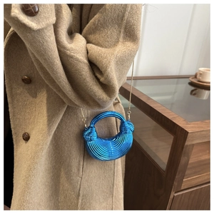 Dettaglio borsa a conchiglia in acrilico blu con trama a righe e catena dorata