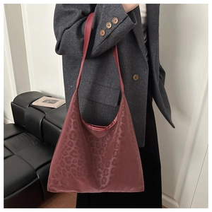 Close-up of wine red leopard print PU leather hobo bag worn by a model in a suit