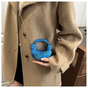 Dettaglio borsa a mezzaluna blu metallizzato con texture su cappotto cammello