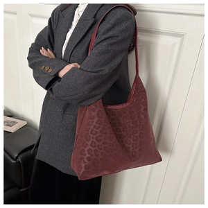 Detail der burgunderroten Hobo-Tasche mit Leopardenmuster, getragen zum grauen Sakko