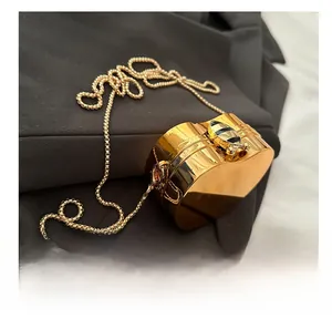 Close-up of golden heart-shaped evening bag featuring a detailed bee metal clasp and bead chain