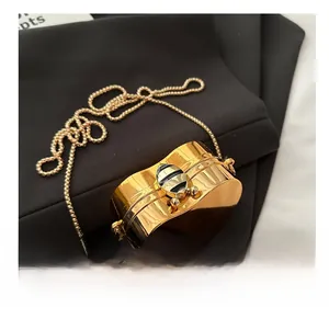 Detail of gold metal evening bag featuring a bee-shaped hardware clasp and chain