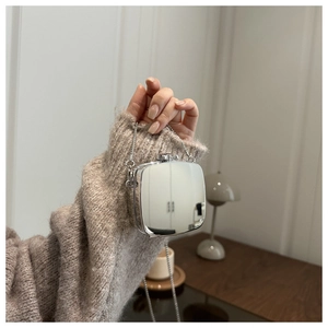 Mini sac boîte en acrylique miroir argenté avec chaîne, porté dans un décor intérieur