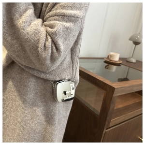 Close-up of a silver mirror mini crossbody bag with metal chain on a beige knit sweater