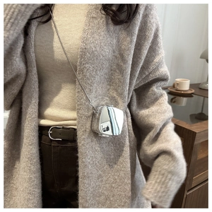 Close-up of a mini silver mirror bag with a fine chain shown in a lifestyle setting