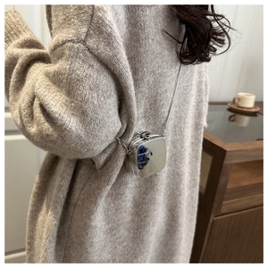 Gros plan du mini sac boîte en acrylique argenté avec chaîne en métal sur pull gris