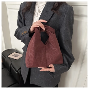 Detail of burgundy leopard print knot bag with soft gathered texture on a grey blazer