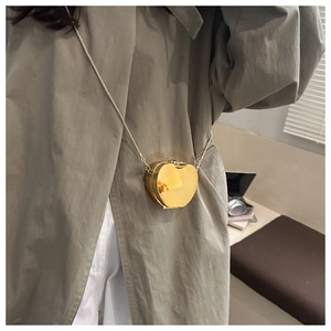 Detail of creative gold apple-shaped mini crossbody bag with a sleek metallic chain strap