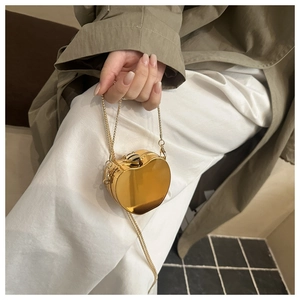 Close-up of a heart-shaped gold metallic mini evening bag with a long chain strap