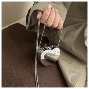 Gros plan d'un mini sac cœur en miroir argenté avec une fine chaîne à perles métal