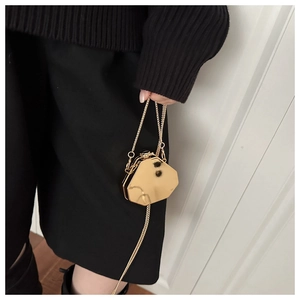Détail macro d'un mini sac octogonal doré brillant avec bandoulière chaîne métallique