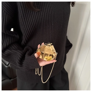 Vue détaillée du mini sac boîte octogonal doré avec chaîne en métal tenu par le mannequin