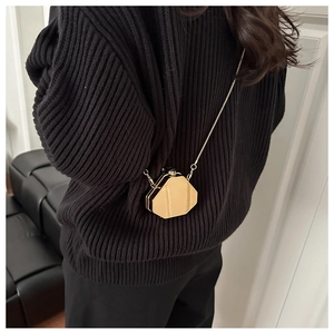 Mini sac géométrique chic en acrylique doré avec bandoulière sur un pull noir