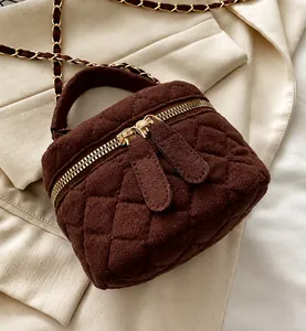 Primer plano del bolso bandolera de terciopelo acolchado marrón con cremalleras