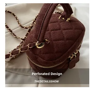 Detalle de bolso caja de ante acolchado marrón oscuro con cadena dorada y doble cremallera