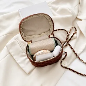 Vista interior del bolso redondo acolchado marrón con espacio para labial y auriculares