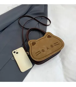 Détail d'un sac à main chat avec broderie à côté d'un téléphone pour comparer la taille