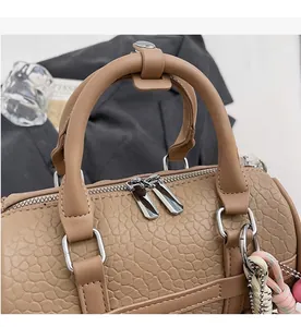 Detailed close-up of premium brown Boston bag featuring dual silver zippers and pebble leather