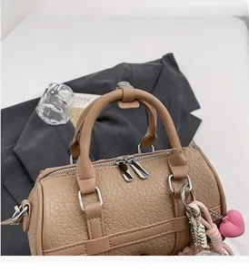 Detail of light brown Boston bag featuring cracked leather texture and heart charm