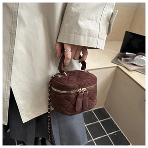 Detalle de bolso cilíndrico acolchado marrón con cadena dorada y doble cremallera