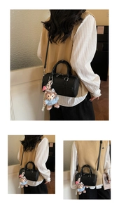 Detail of black leather Boston bag featuring pebbled texture and plush bear charm