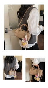 Detail view of beige Boston bag with lychee texture and cute plush bear accessory