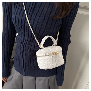 Detalle de bolso caja de ante acolchado blanco con cadena dorada usado por una modelo