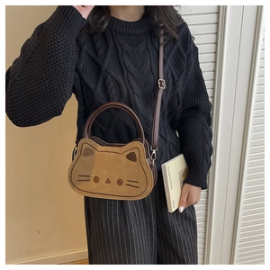 Détail d'un sac bandoulière en forme de chat avec broderies et cuir marron bicolore élégant