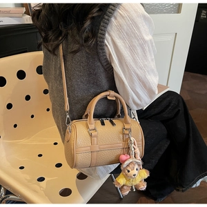 Chic beige Boston bag in lychee texture leather held by a model in an indoor setting