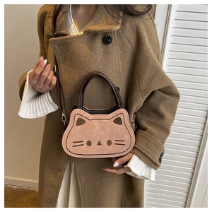 Dettaglio della mini borsa rosa a forma di gatto con ricamo su cappotto di lana marrone