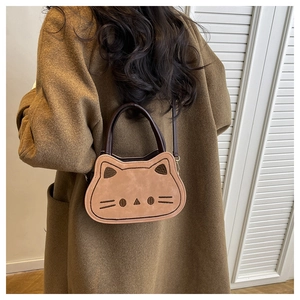 Détail d'un sac bandoulière marron en forme de chat avec broderie sur manteau