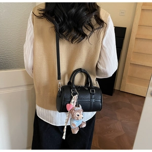 Detail of black Boston bag featuring lychee texture and cute bear plush charm accessory