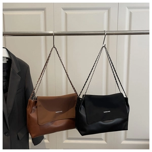 Detail of flap shoulder bags in brown and black with chain straps and fashion lettering