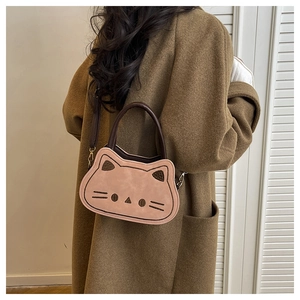 Sac bandoulière chat rose porté par un mannequin en manteau de laine marron élégant