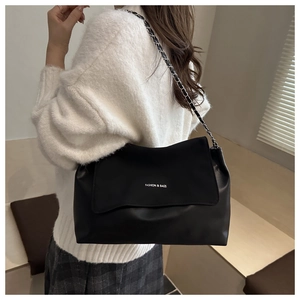 Detail of black leather tote bag with silver chain strap and fashion logo engraving