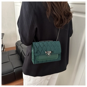 Close-up of dark green velvet crossbody bag with diamond quilting and silver chain