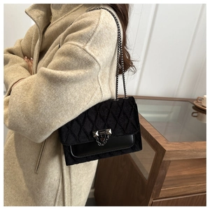 Close-up of quilted black crossbody bag with metal chain strap and studded buckle detail